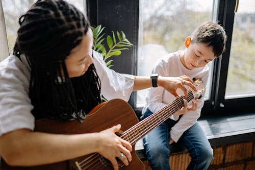 Free A Boy Learning How to Play Acoustic Guitar Stock Photo