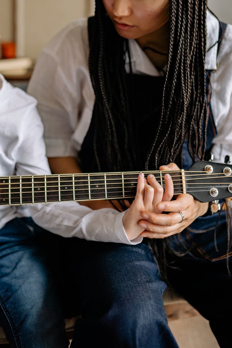 Woman Teaching A Child How To Play The Guitar