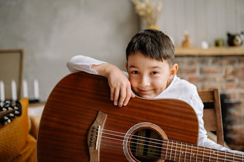 Free Cute Young Boy in White Shirt Holding Brown Acoustic Guitar Stock Photo
