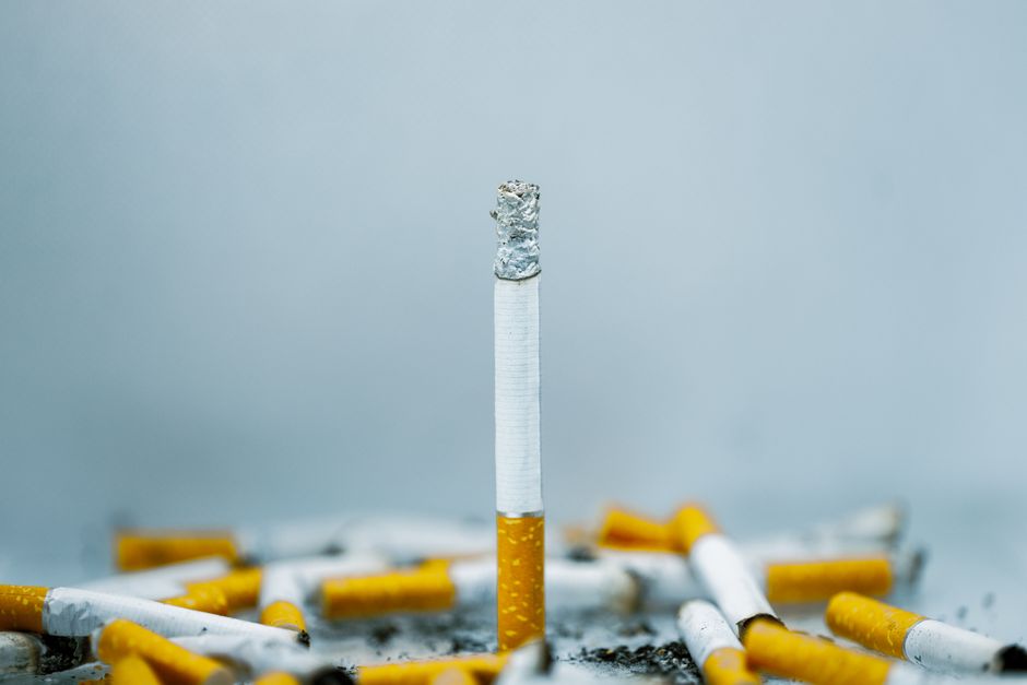 A close-up image of cigarette butts scattered on a white surface, highlighting tobacco addiction. A close-up image of cigarette butts scattered on a white surface, highlighting tobacco addiction.