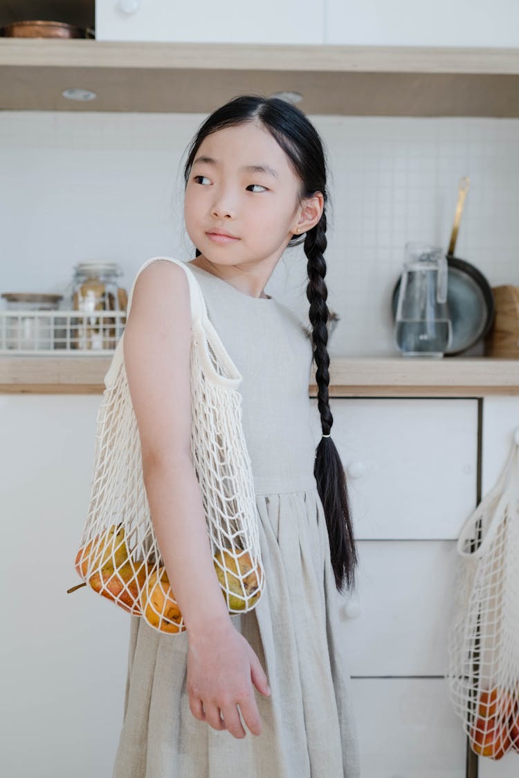 Girl In Beige Dress Carrying Mesh Bag On Her Shoulder