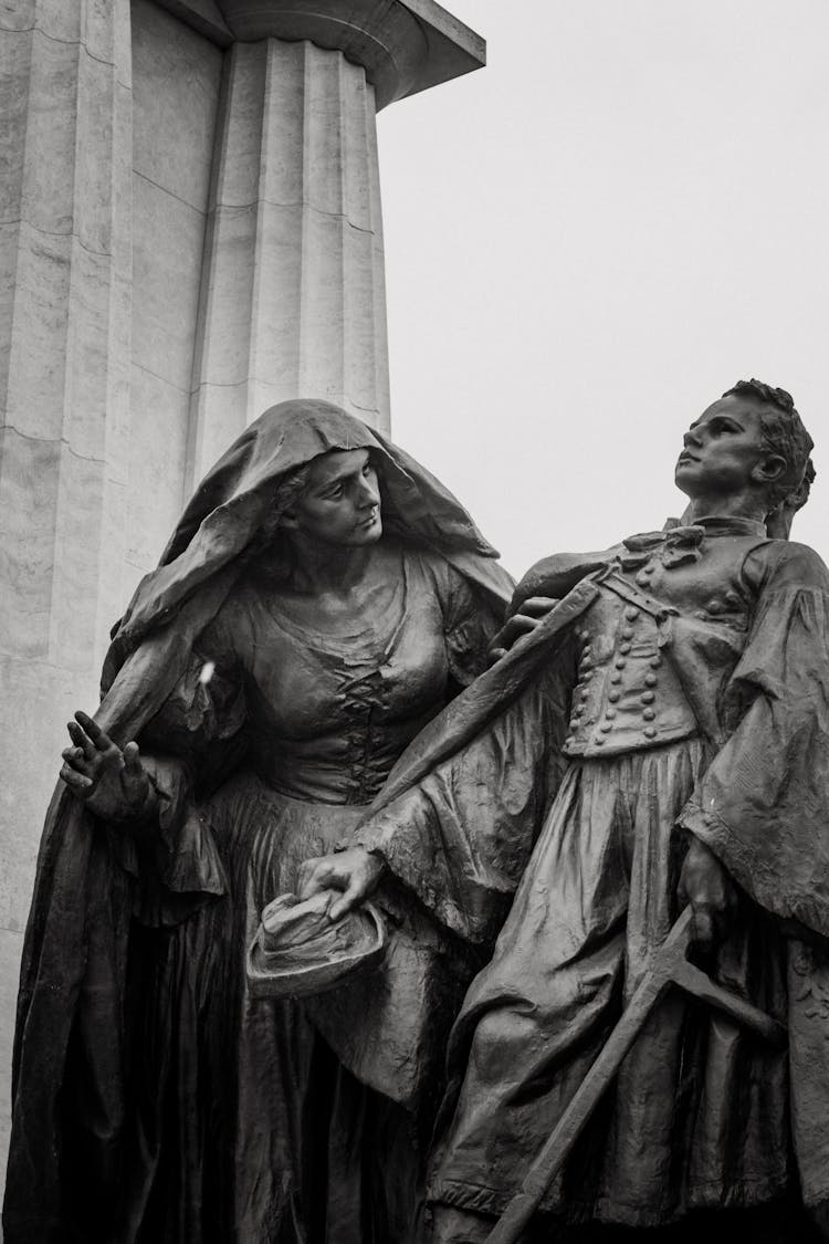 Statue Of Woman Looking At Man Holding A Sword