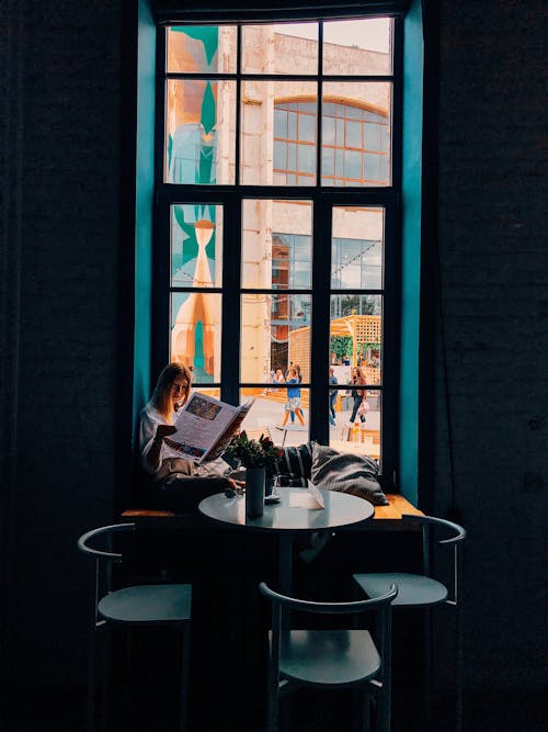 Woman Sitting on Window Sill Reading Newspaper