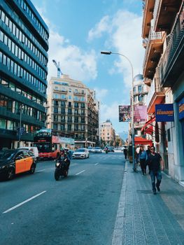 Urban Barcelona scene with pedestrians and traffic on a sunny afternoon. Captures vibrant city life.