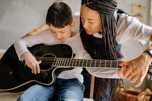 Free Woman Teaching a Kid to Play a Guitar Stock Photo