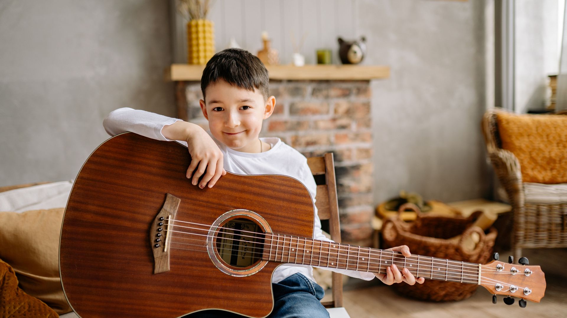 Child learning guitar indoors with an acoustic guitar. Cozy home setting — popular for beginners