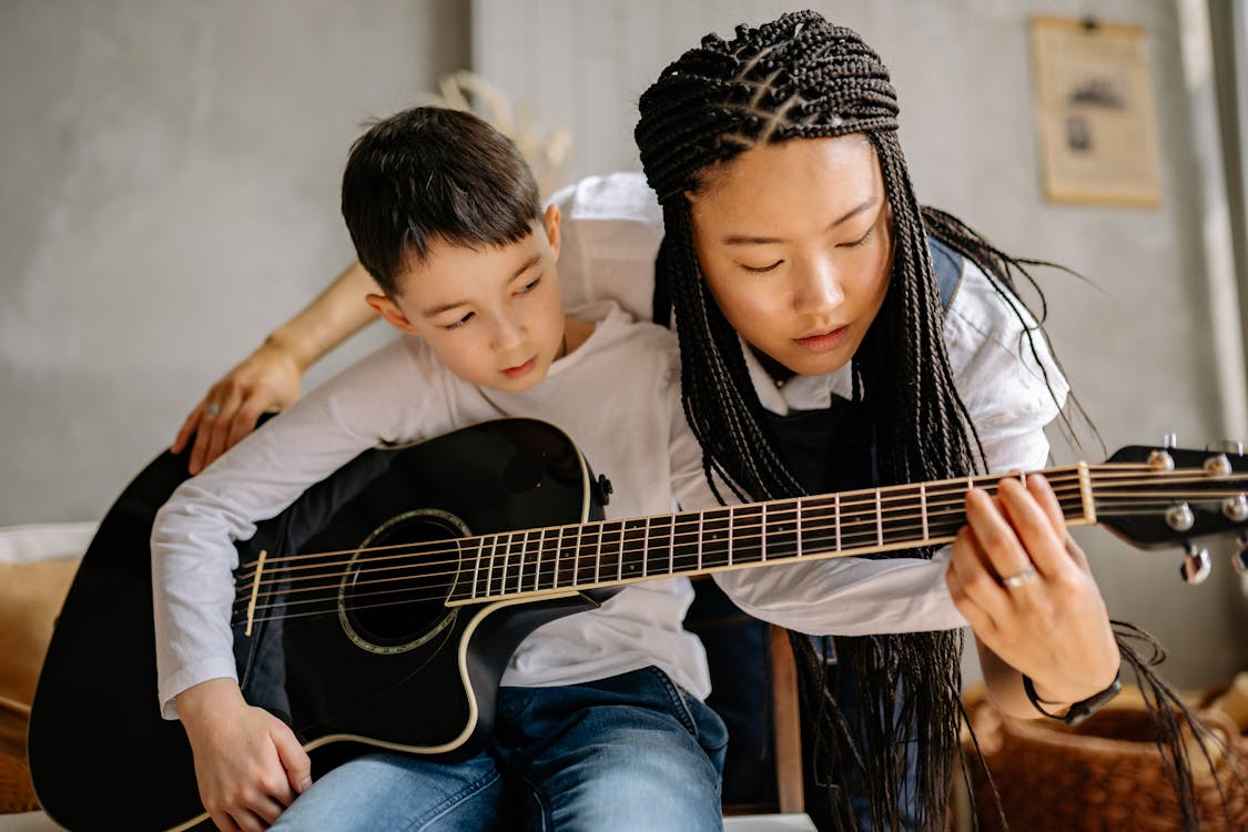 Woman with Braided Hair Teaching a Boy in Playing Guitar · Free Stock Photo