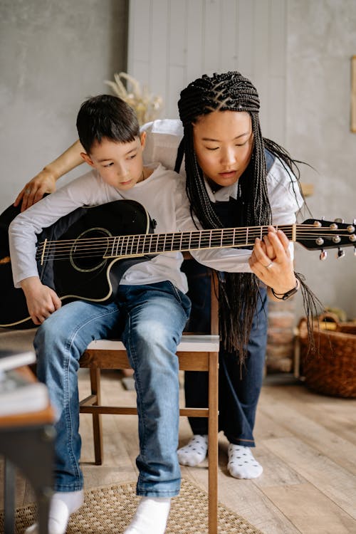 Free A Boy Learning to Play a Guitar with an Instructor Stock Photo