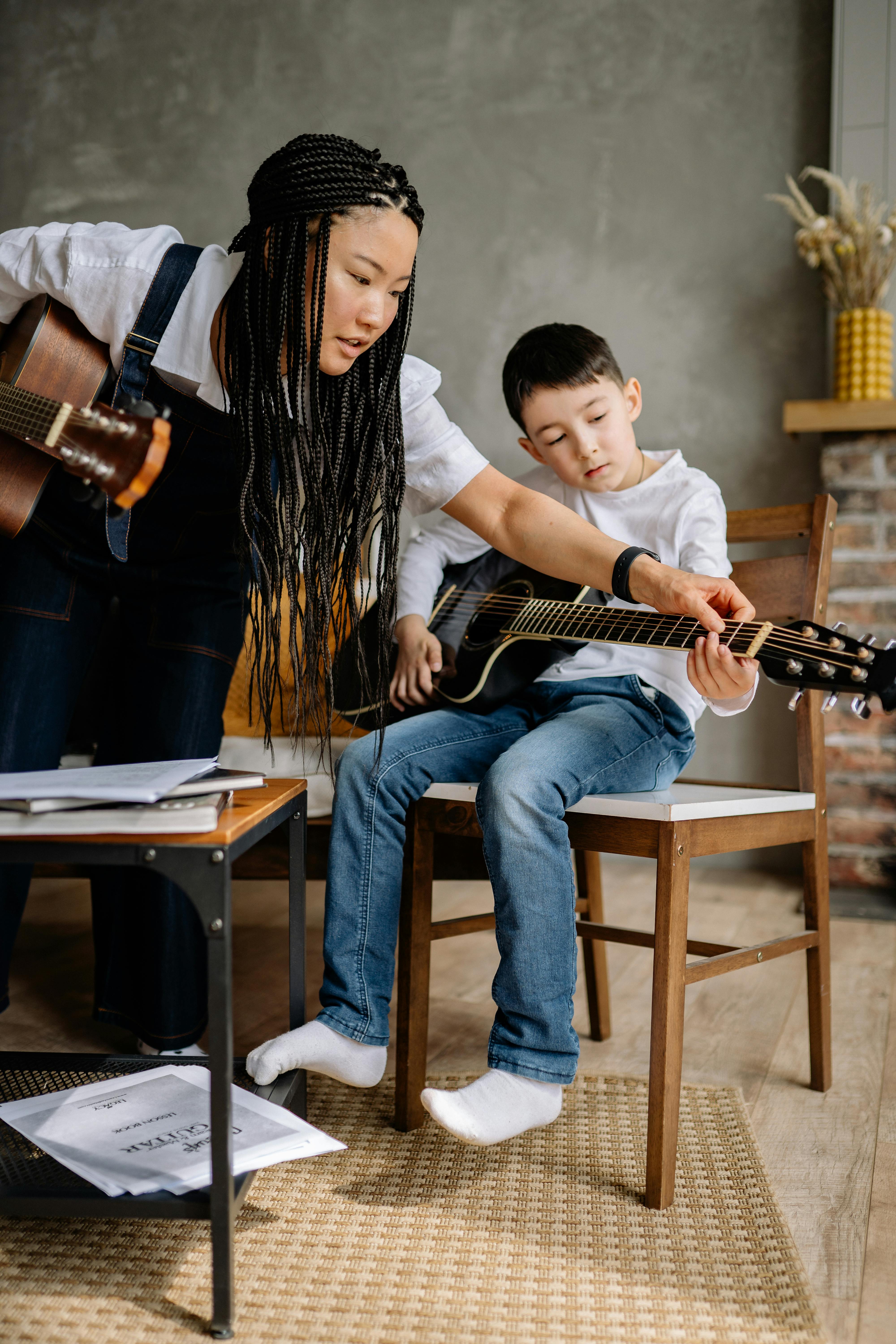 Woman with Braided Hair Teaching a Boy in Playing Guitar · Free Stock Photo Woman with Braided Hair Teaching a Boy in Playing Guitar · Free Stock Photo