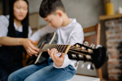 Free Young Boy Leaning to Play a Guitar Stock Photo