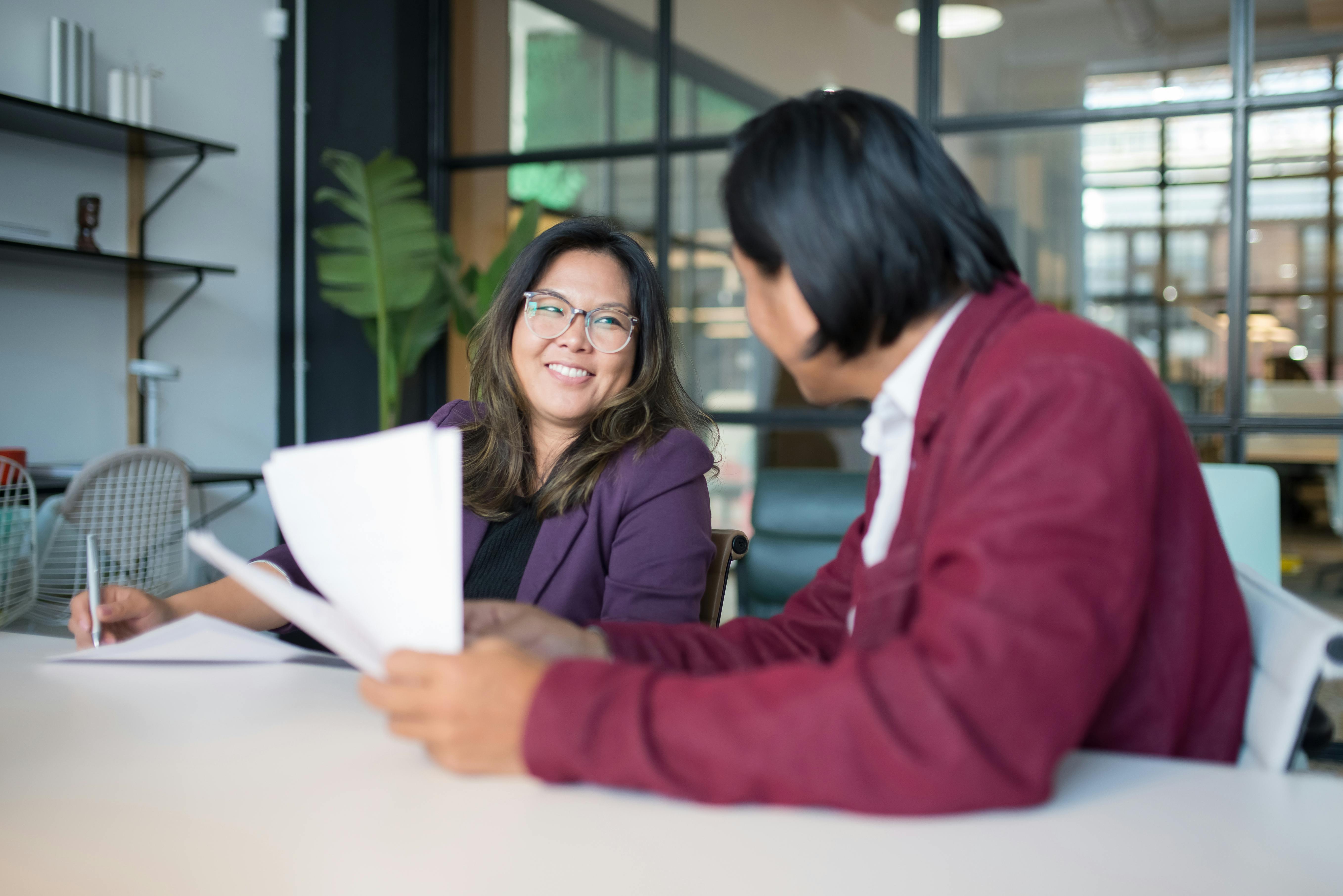 woman in purple blazer smiling while holding a pen