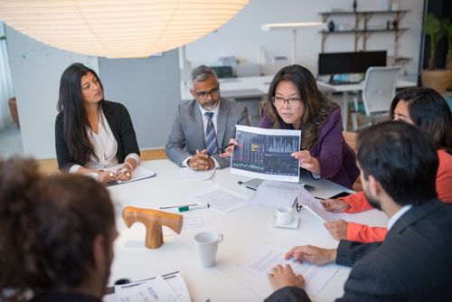Free Multicultural team discussing analytics in a professional business meeting setting with data charts. Stock Photo