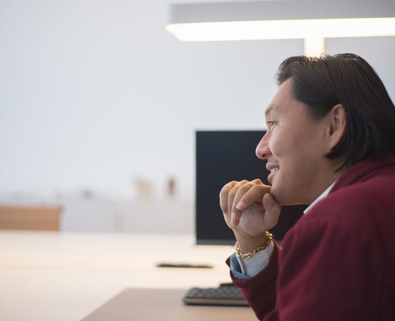 A person sitting at a desk with motivational quotes on the wall, looking contemplative.