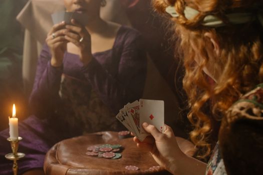Two women playing cards by candlelight, creating a cozy and mysterious atmosphere.
