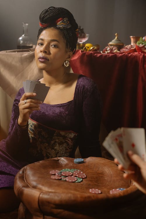 Woman in Purple Long Sleeve Dress Holding Black and White Playing Cards