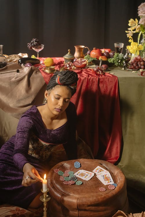 Woman in Purple Long Sleeve Dress Lighting a Candle