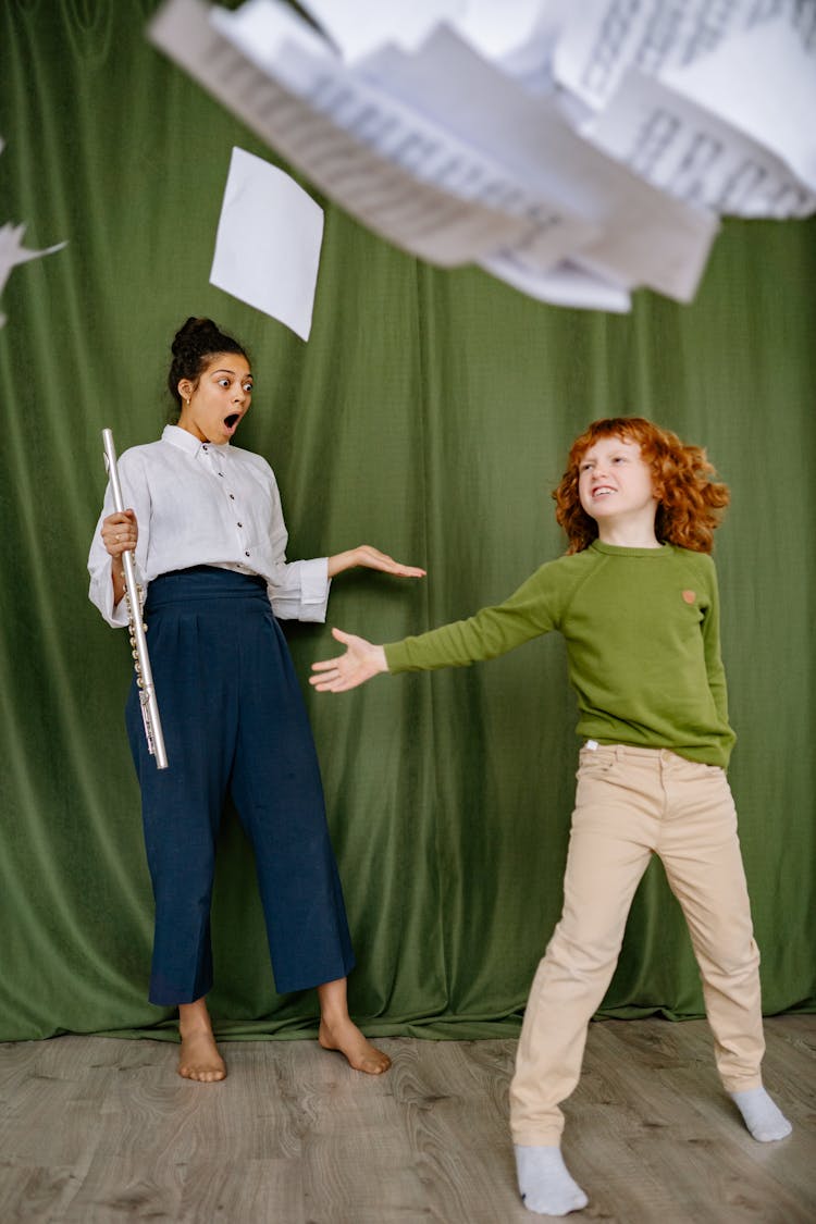 Shocked Woman Holding A Flute And Looking At A Boy Throwing Music Sheets In The Air 