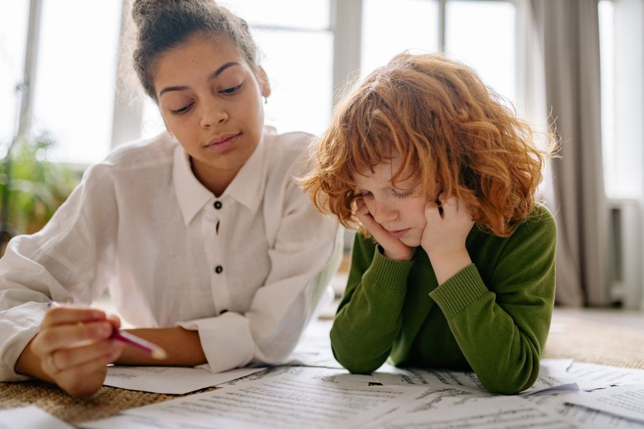 understanding the balance sheet equation for clarity - A child and a woman engaged in a music lesson, focusing on reading music sheets indoors.