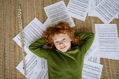 A Boy Lying Down on Musical Notation Papers