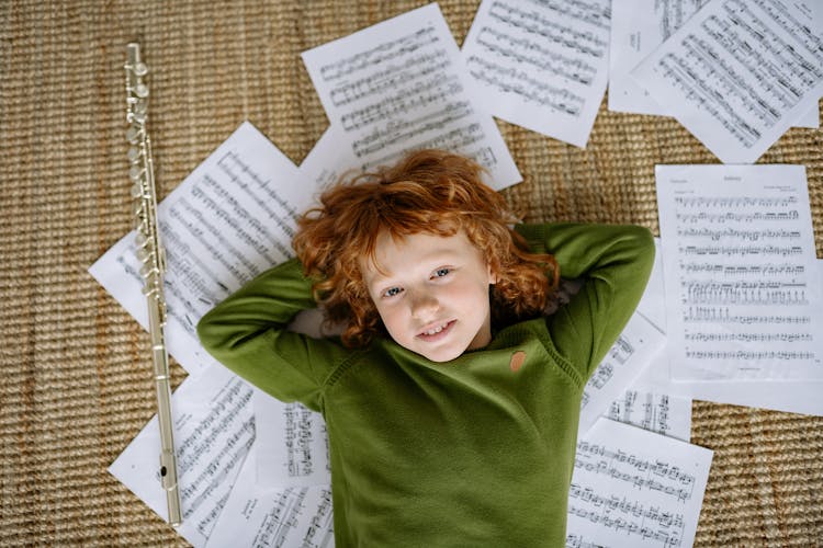 A Boy Lying Down On Musical Notation Papers