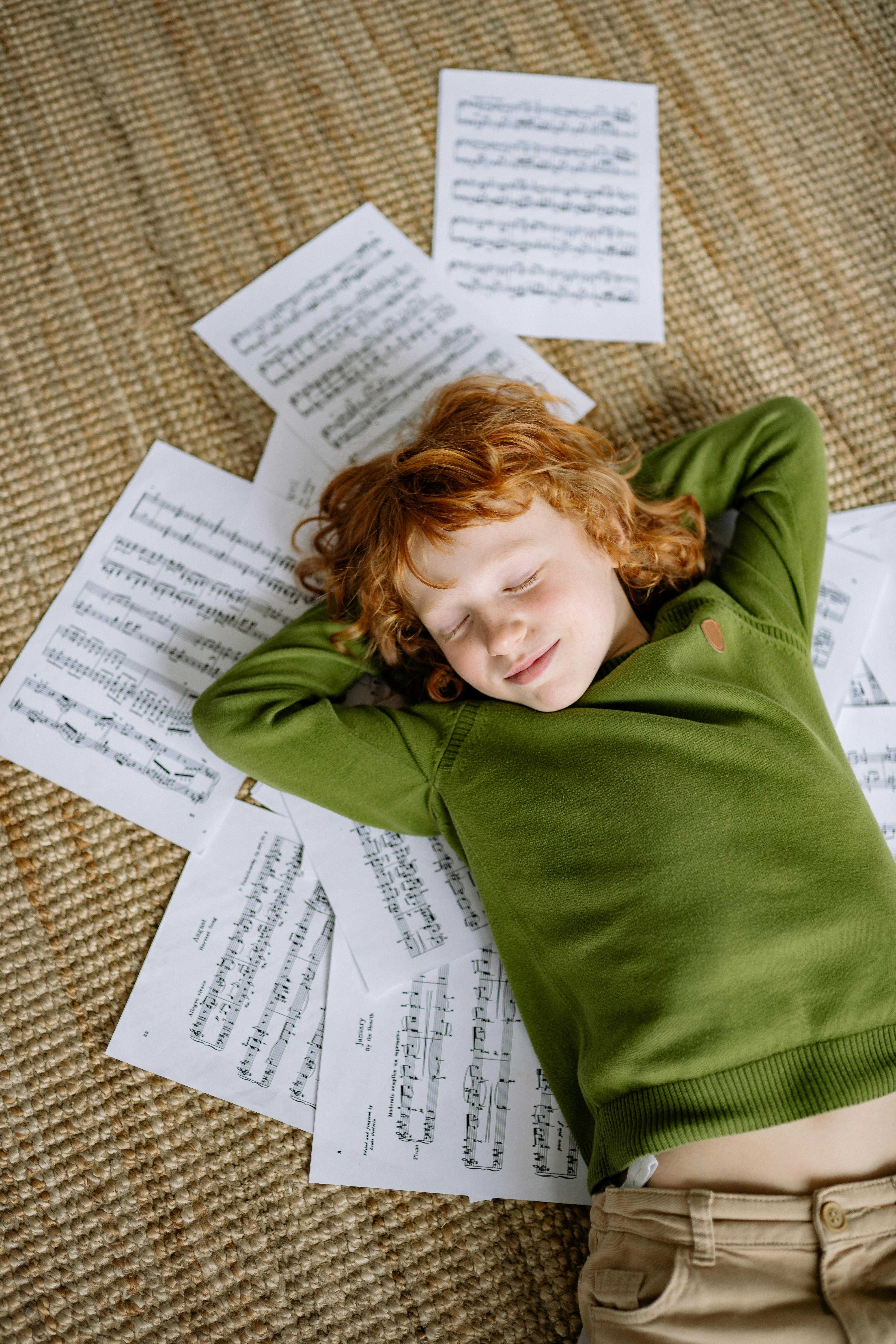 a boy lying down on musical notation papers