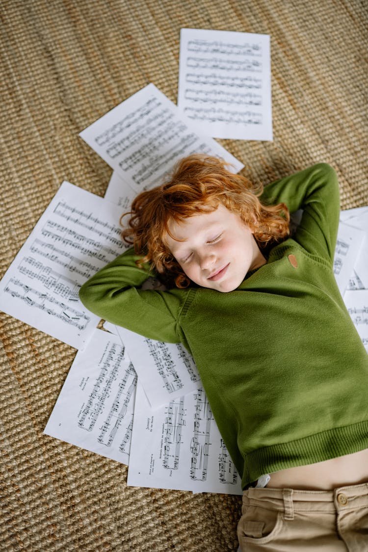 A Boy Lying Down On Musical Notation Papers