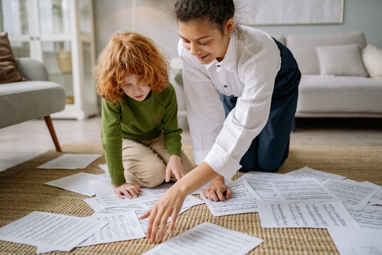 A Woman And A Child Picking Up Musical Notation Papers