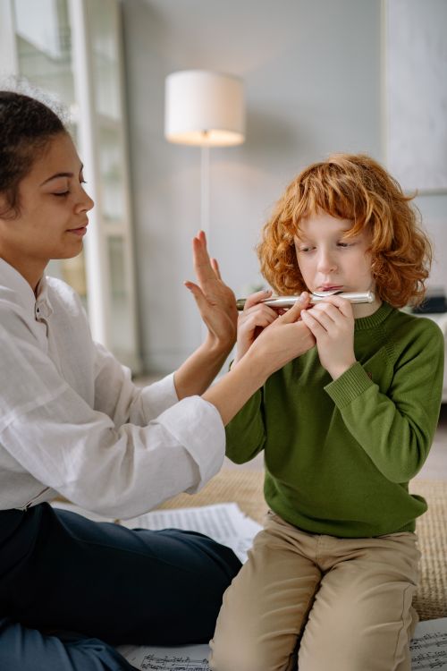 Free A young boy receives flute lessons from a teacher at home, fostering musical skills. Stock Photo