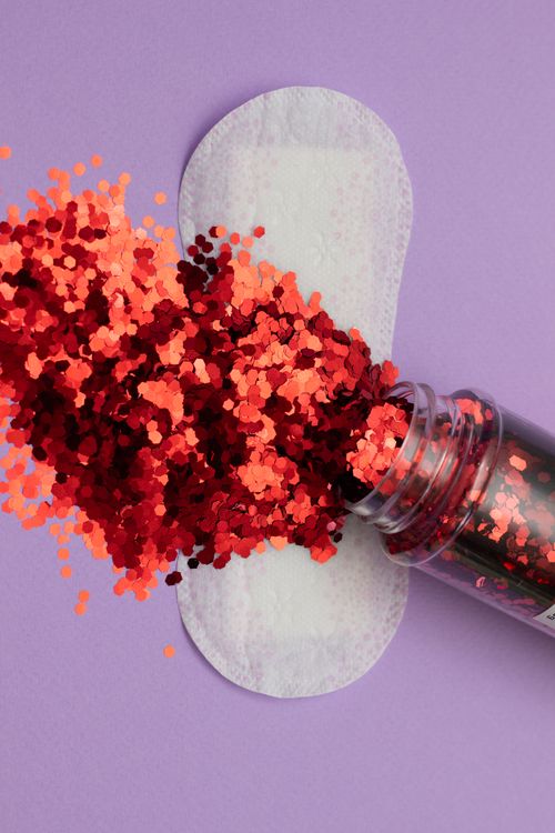 Free Artistic take on feminine hygiene featuring a sanitary pad and glitters on purple backdrop. Stock Photo