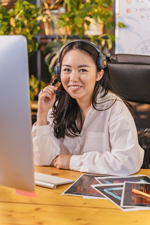 A Woman in White Long Sleeves Smiling while Holding a Headset with Microphone