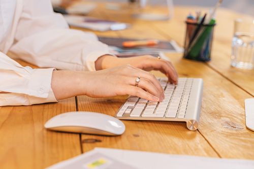 Free Close-up of woman's hands typing on a keyboard, showcasing modern office environment. Stock Photo