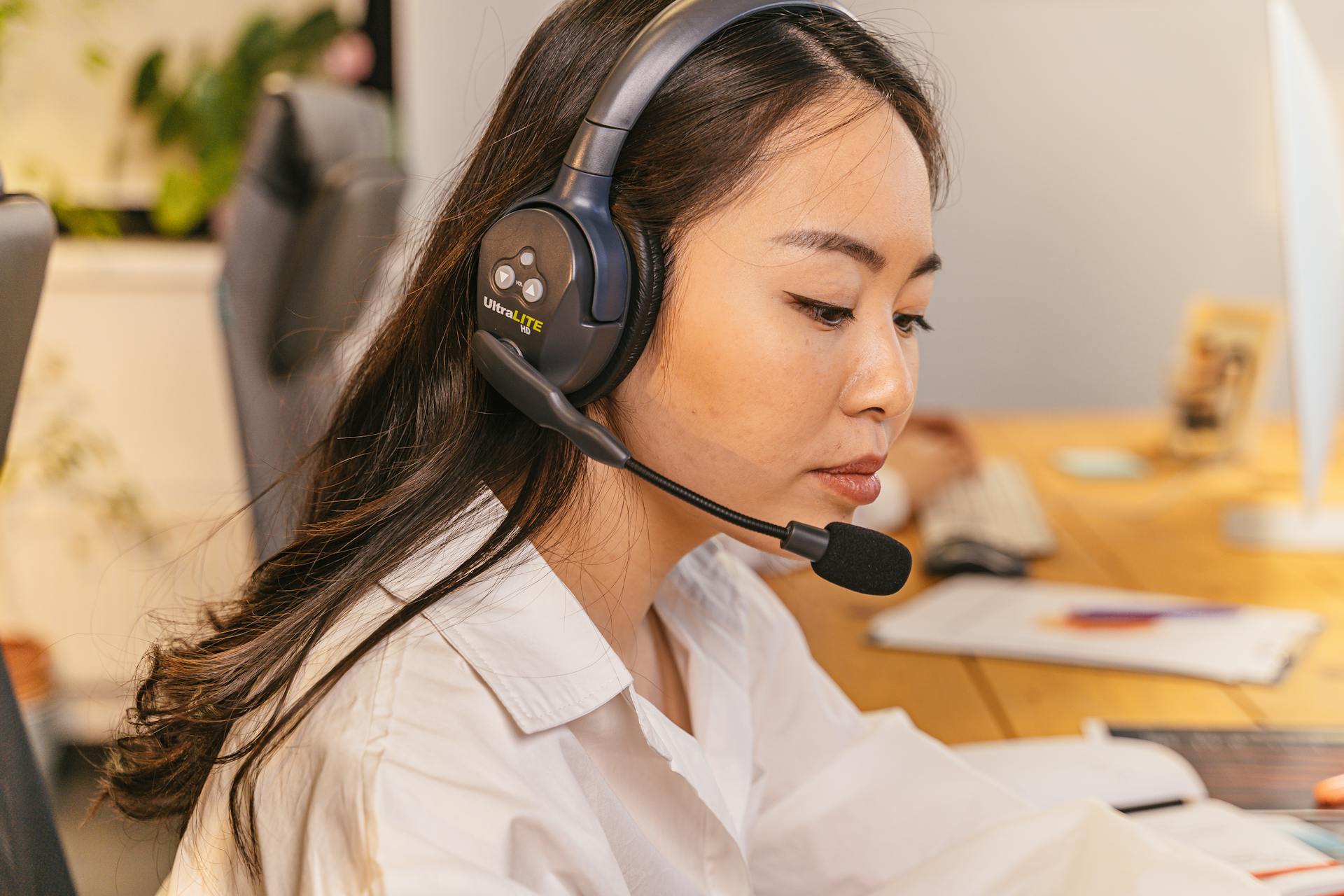 A professional woman wearing a headset, concentrating on her work at the office.