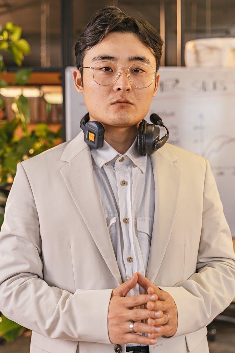 A Man In A Business Suit With A Headset On His Neck