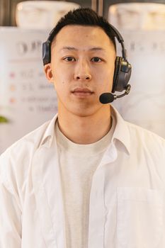 Close-up portrait of an adult man wearing a headset in a business environment. Professional attire.