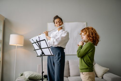 Free A woman teaching a young boy to play the flute indoors during a music lesson. Stock Photo