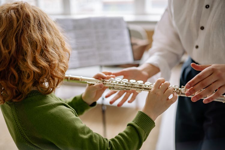 Teacher Teaching A Child How To Play A Flute