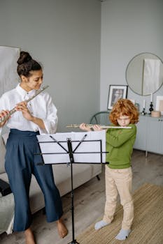 A child learning to play the flute with a teacher at home, focused on music sheets.