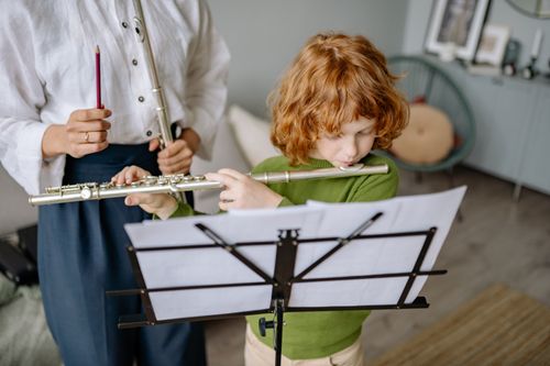 Free A young boy learning to play the flute during a music lesson indoors. Stock Photo