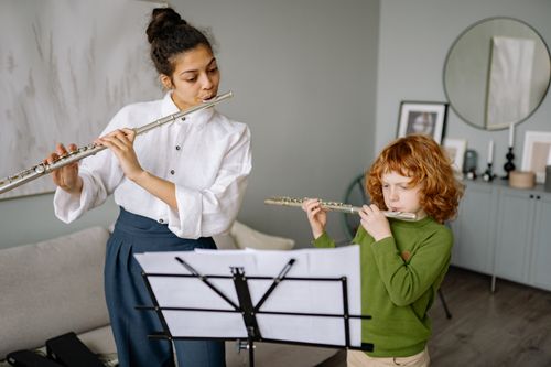 Free A child learning to play the flute with a teacher during a music lesson at home. Stock Photo
