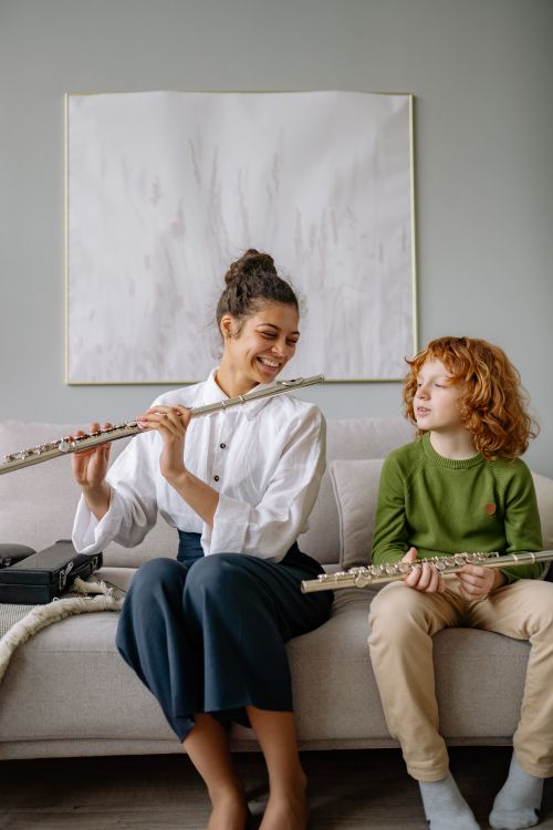 Free Smiling mother and son enjoying flute practice together indoors. Stock Photo