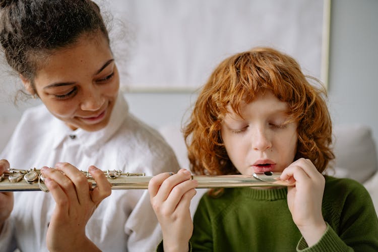 A Woman Teaching A Boy How To Play A Flute