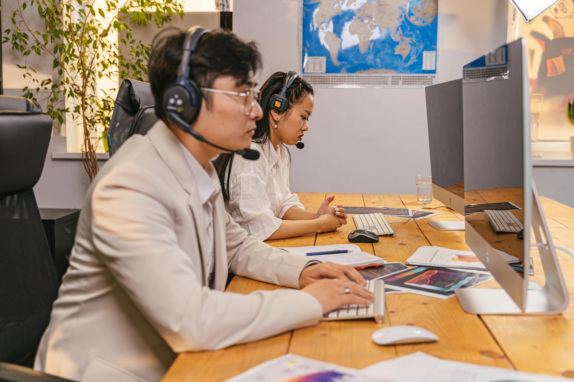 Call center agents working at computers with headsets in a modern office setting.