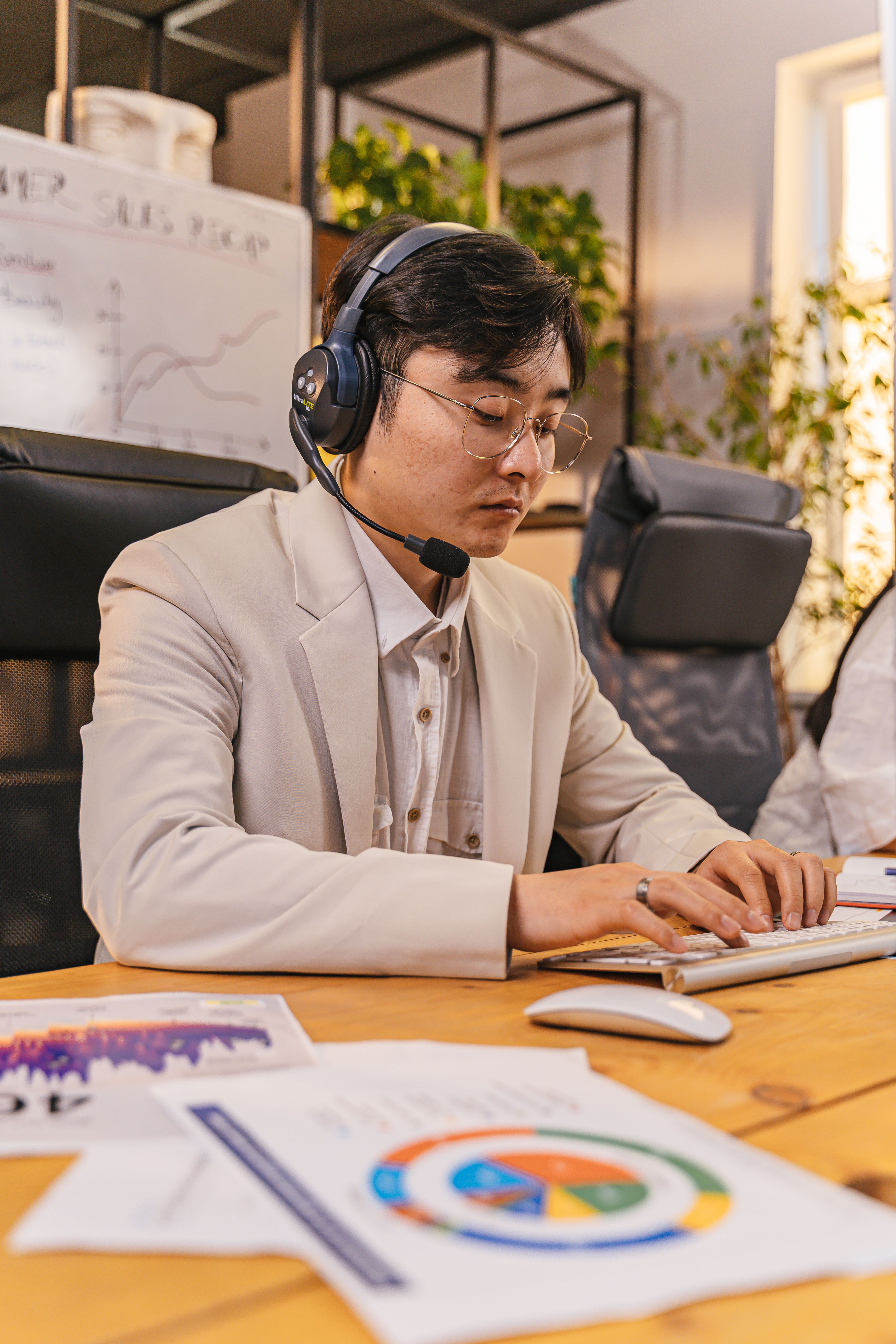 Focused professional man wearing headphones, typing at desk in a home office setting with a modern interior.