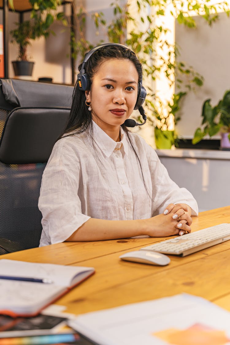 Portrait Of A Woman Wearing A Headset And Sitting At The Desk 