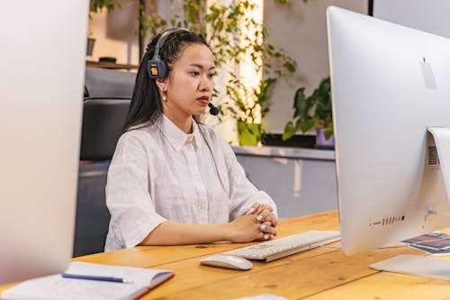 Woman with Headphones and Mic Working in an Office on Computer 