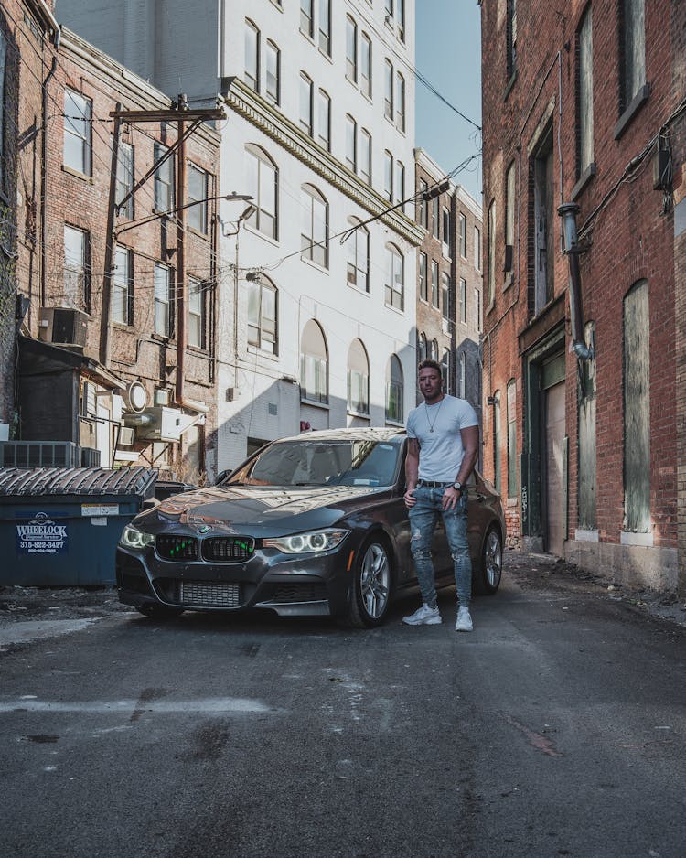 Man Standing By Luxurious Car Parked In Backstreet