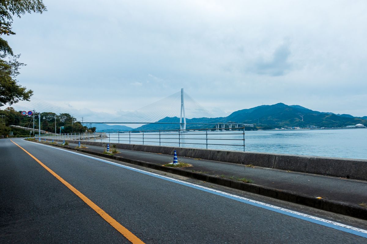 A scenic coastal road along the Onomichi coastline with a bicycle, near the start of the Shimanami Kaido