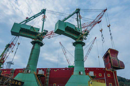 Low Angle Shot of Cranes and a Large Ship in the Port 