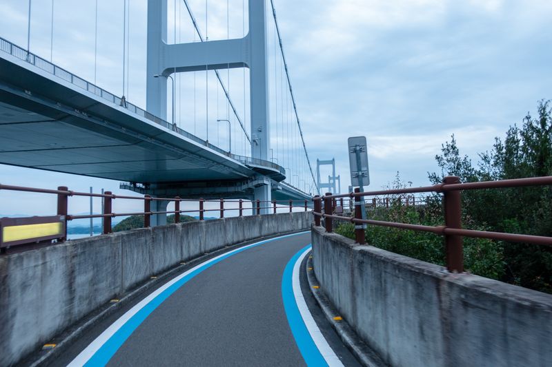 The Shimanami Kaido cycling lane: the distinctive blue-marked cycle path running under a suspension bridge over the Seto Inland Sea, Ehime