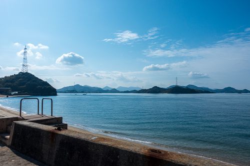 Free Tranquil view of the seaside embankment at Onomichi, Hiroshima with blue sky and islands. Stock Photo